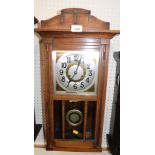 An oak cased 1920's/1930's wall clock, the moulded cornice above a brass and silvered coloured numer