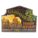 A Guinness Irish Stout wooden advertising sign, the arched top on a black painted border with raised