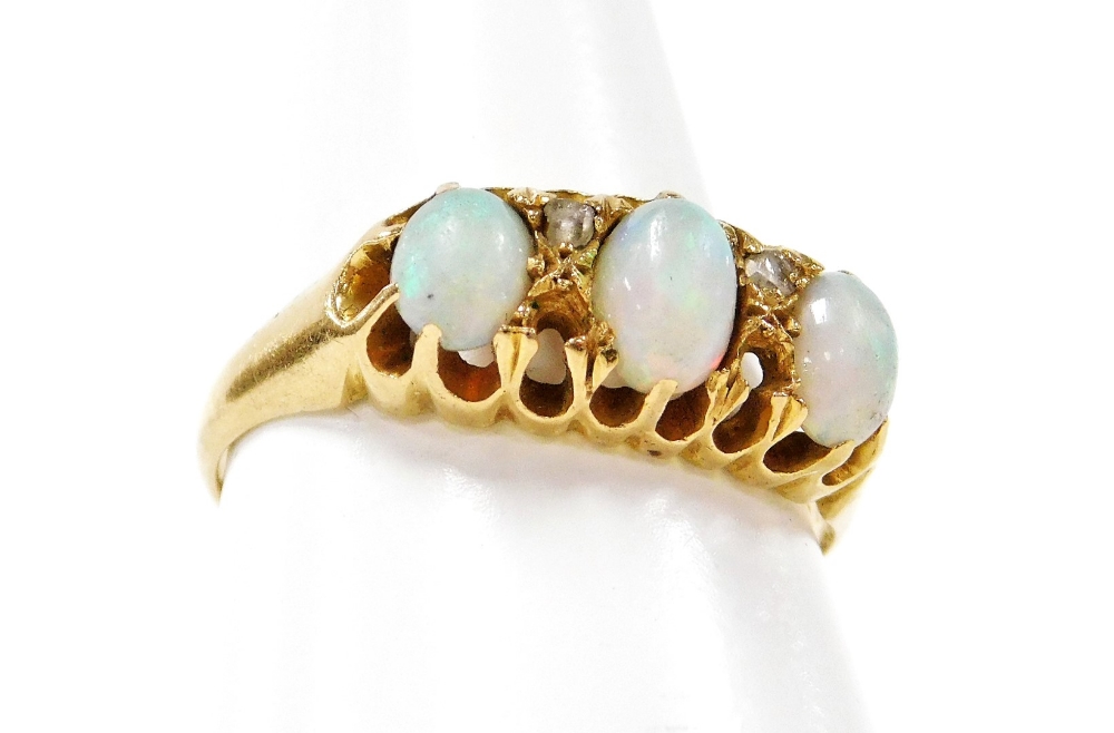 An 18ct gold opal and diamond dress ring, with three oval opals each in claw setting, and design of