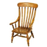 A Victorian oak lath back grandmother chair, with solid saddle seat, raised on turned legs united by