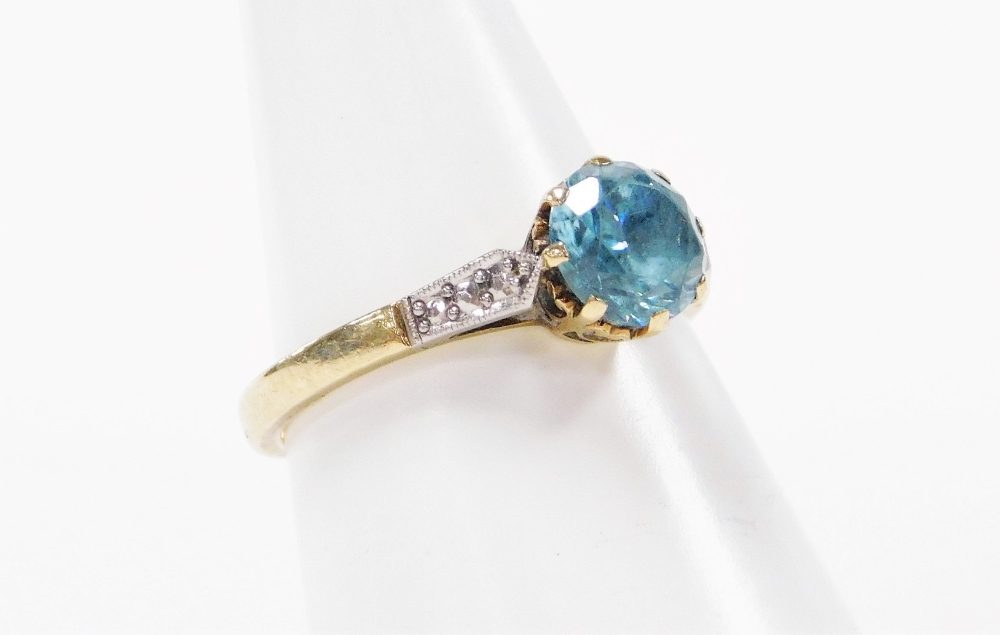 An aquamarine dress ring, the central aquamarine in claw setting, with white metal shoulders on a ye