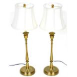 A pair of burnished brass candlestick formed table lamps, with white octagonal shades, 84cm high.