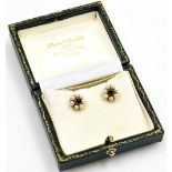 A pair of cultured pearl and garnet set floral studs, each with central garnet in claw setting surro