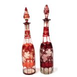 A near pair of late 19thC Continental ruby glass graduated decanters and stoppers, etched with scrol