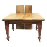 A Victorian oak wind out dining table with two additional leaves, raised on tapering square legs and