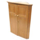 A 19thC pine hanging corner cabinet, with a dentil cornice above two panelled doors, 106cm high,