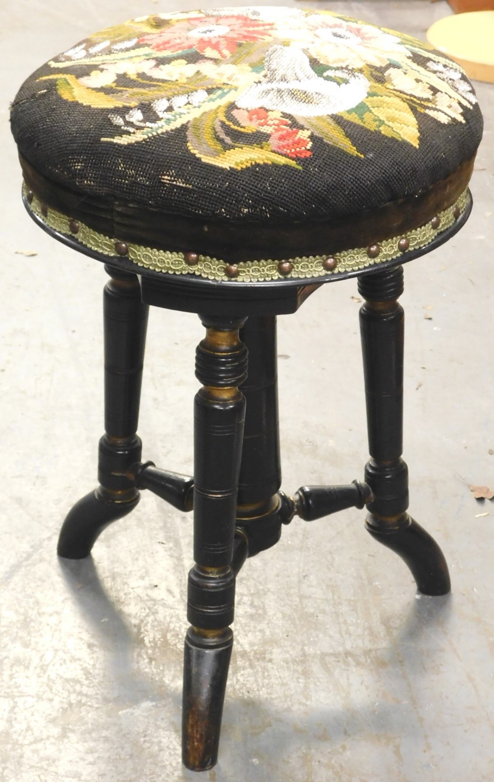 A Victorian ebonised and parcel gilt adjustable piano stool, the circular top decorated with