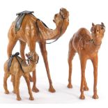 A graduated set of three leather covered style camels, 32cm high, etc. (3)