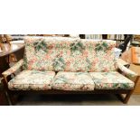A 1960's teak Guy Rogers Virginia style three seater sofa, with later floral cushions to the