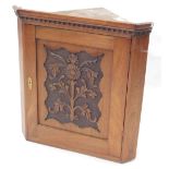 An Edwardian walnut hanging corner cabinet, the door carved with flowers and leaves, 64cm high, 60cm