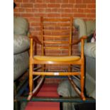 A mid century beech ladder back rocking chair. The upholstery in this lot does not comply with the 1