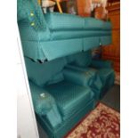 A three piece suite upholstered in green patterned fabric.