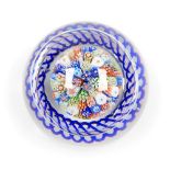 A Baccarat millefiori glass paperweight, with radial blue twist and lace canes, within a cobalt blue