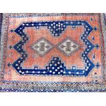 A Turkish rug, decorated with central lozenge in blue, on an orange ground with multiple borders, 20