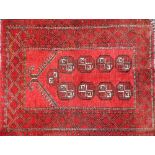 A Beluchi type prayer rug, with a design of medallions, on a deep red ground with one wide border, 1