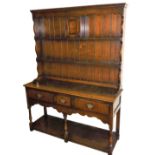 An 18thC style oak dresser, the upper section with a Delft rack, centred by a cupboard, raised above