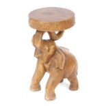 An Eastern hardwood carved elephant table, the circular drum top with floral detailing, held by an e