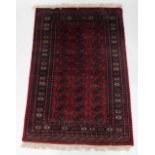 An Afghan Belouch rug, with three rows of medallions in blue, on a red ground with multiple border,