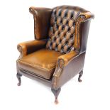 A brown leather Chesterfield wingback armchair, with button back and stud detailing, on out splayed