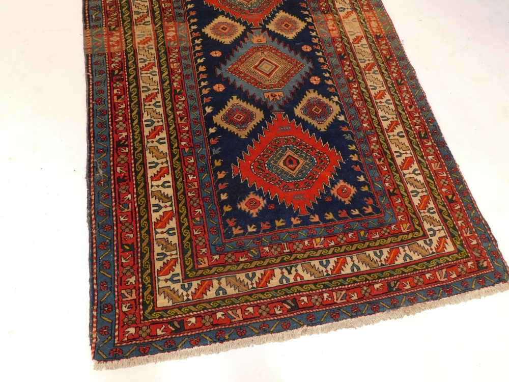 A Persian Kazak type rug, with three geometric medallions in deep orange and pale blue, on a blue gr - Image 2 of 3