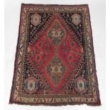 A Persian rug, with two lozenge shaped medallions, in green on a red ground with black spandrels dec
