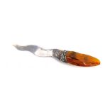 A Harold Popkiewicz amber handled letter opener, the shaped and polished amber in a white metal blad