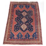 A Persian Afshar rug, with a three cream lozenges on a blue ground, within a shaped border, geometri