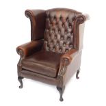 A brown leather Thomas Llyod Chesterfield wingback armchair, with button and stud detailing on mahog