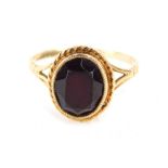 A 9ct gold garnet dress ring, with faceted garnet in rub over setting with rope twist borders and V