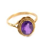 A 9ct gold dress ring, with oval central amethyst with rope twist and flared design outer border on