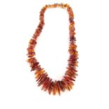 An amber graduated necklace, with various sliced pieces of amber, strong orange colouring, on a stri