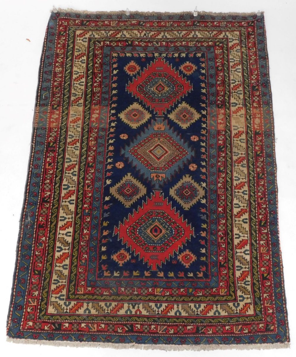 A Persian Kazak type rug, with three geometric medallions in deep orange and pale blue, on a blue gr