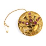An early 20thC gilt metal circular brooch, with central floral spray, set with pink paste stones, on