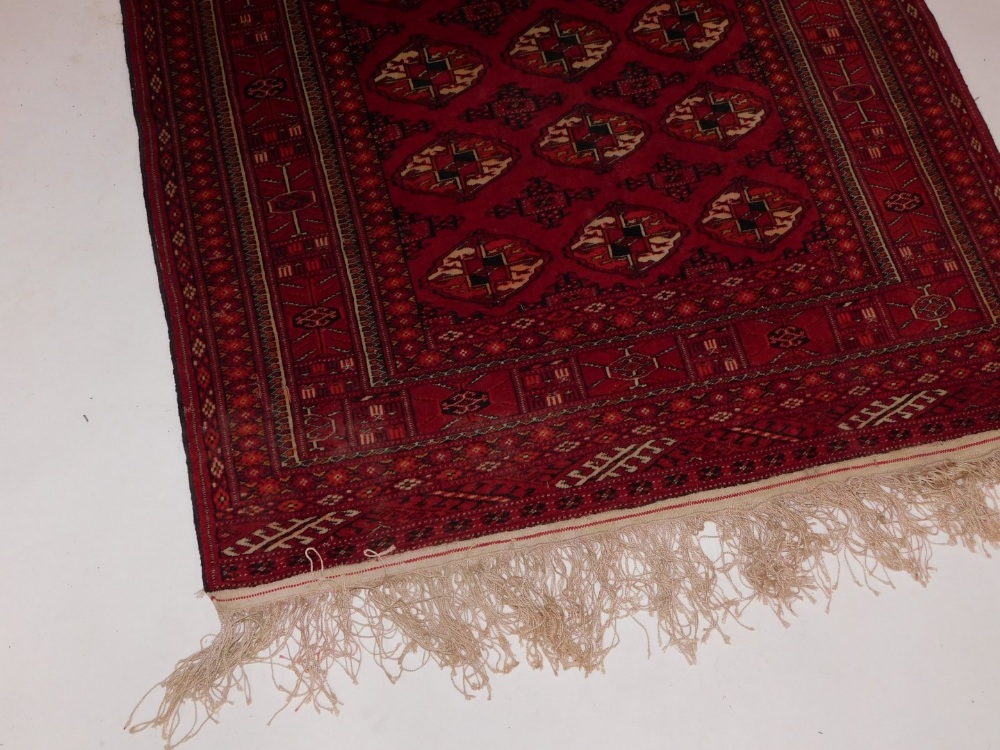 An Afghan Belouch rug, with three rows of medallions on a red ground, within multiple borders, 106cm - Image 2 of 3
