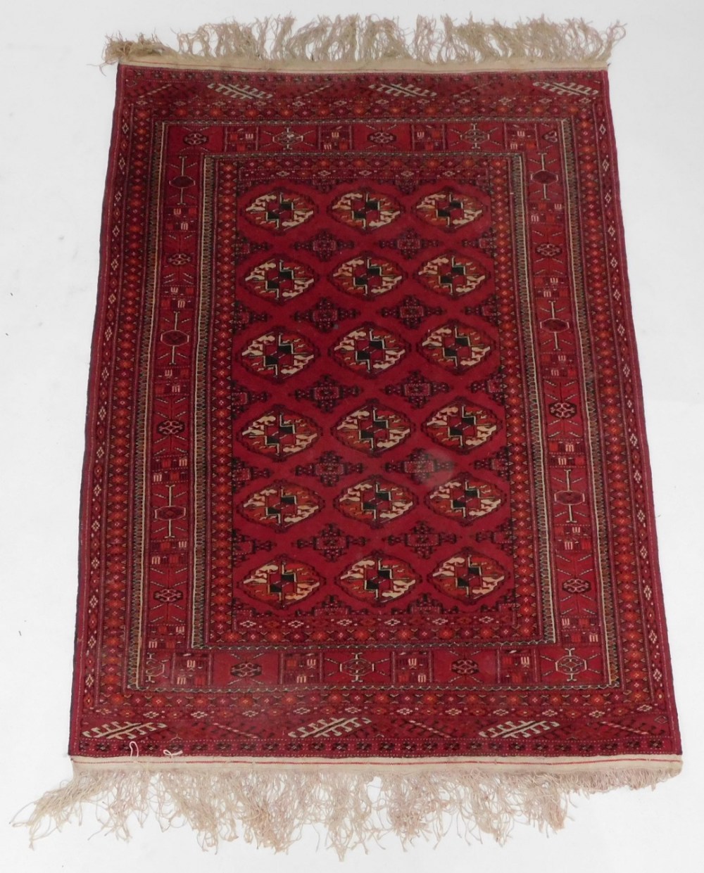 An Afghan Belouch rug, with three rows of medallions on a red ground, within multiple borders, 106cm