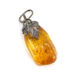 An amber pendant, the shaped amber with a white metal clasp, arched over and pierced through the sto