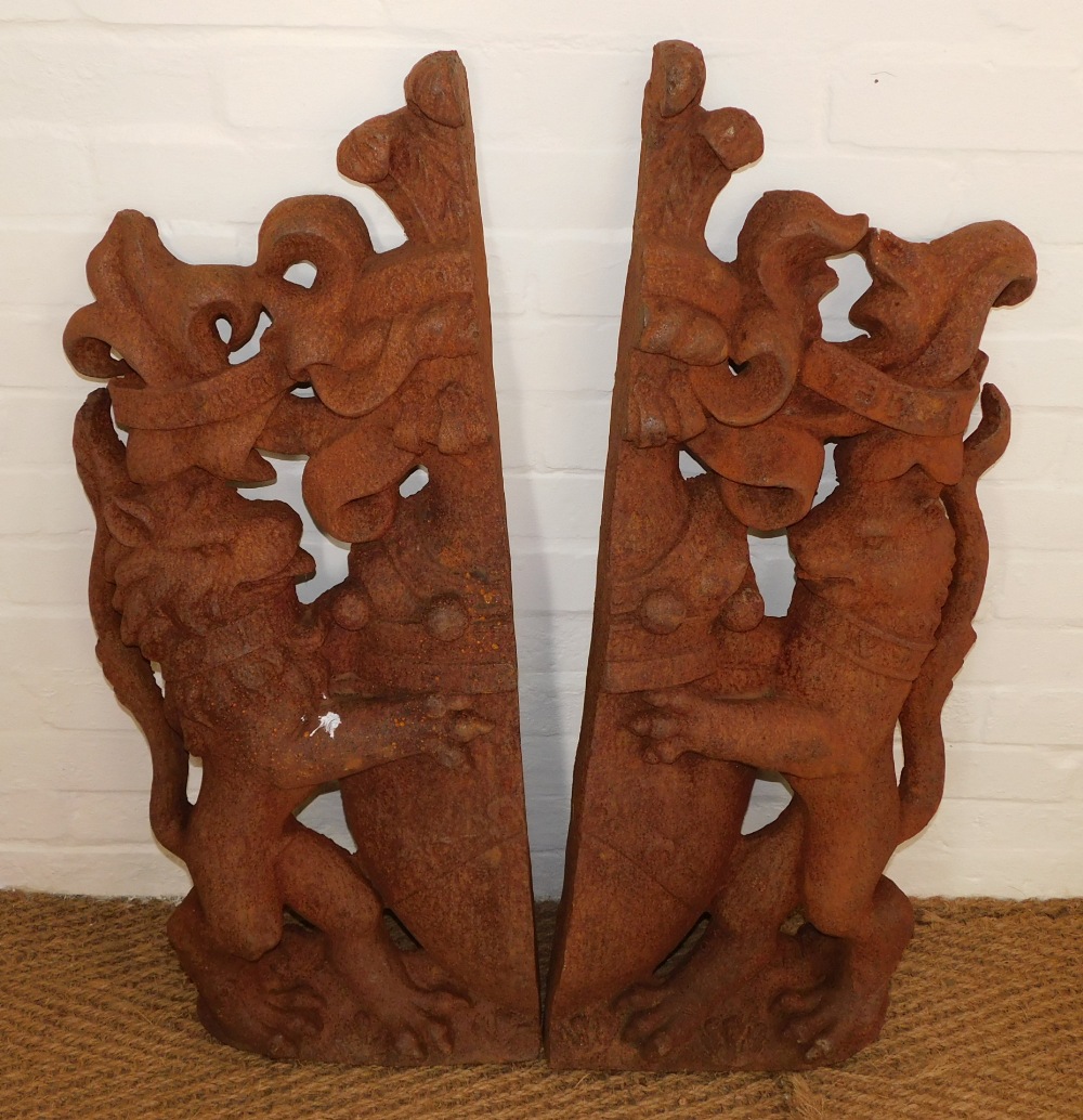 A pair of cast iron lion shield crests, each half the picture, with lion holding crest, bearing rubb