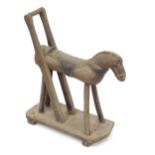 A vintage child's wooden pull along toy horse, with leather saddle on a wooden base, 46cm wide.