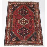 A Persian rug, with a central medallion in cream, navy, red, etc, on a red ground with spandrels, su
