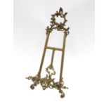 A brass rococo style photo stand, the arched top, with single leg back, 58cm high.