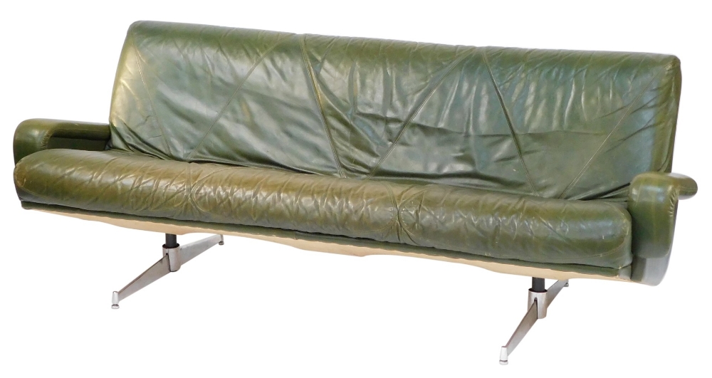 A 1960's vintage green leather three seater sofa, raised on twin chrome plated and cast iron support