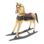 A painted pine rocking horse, with applied red saddle in Eastern design, on a blackened base, 95cm h