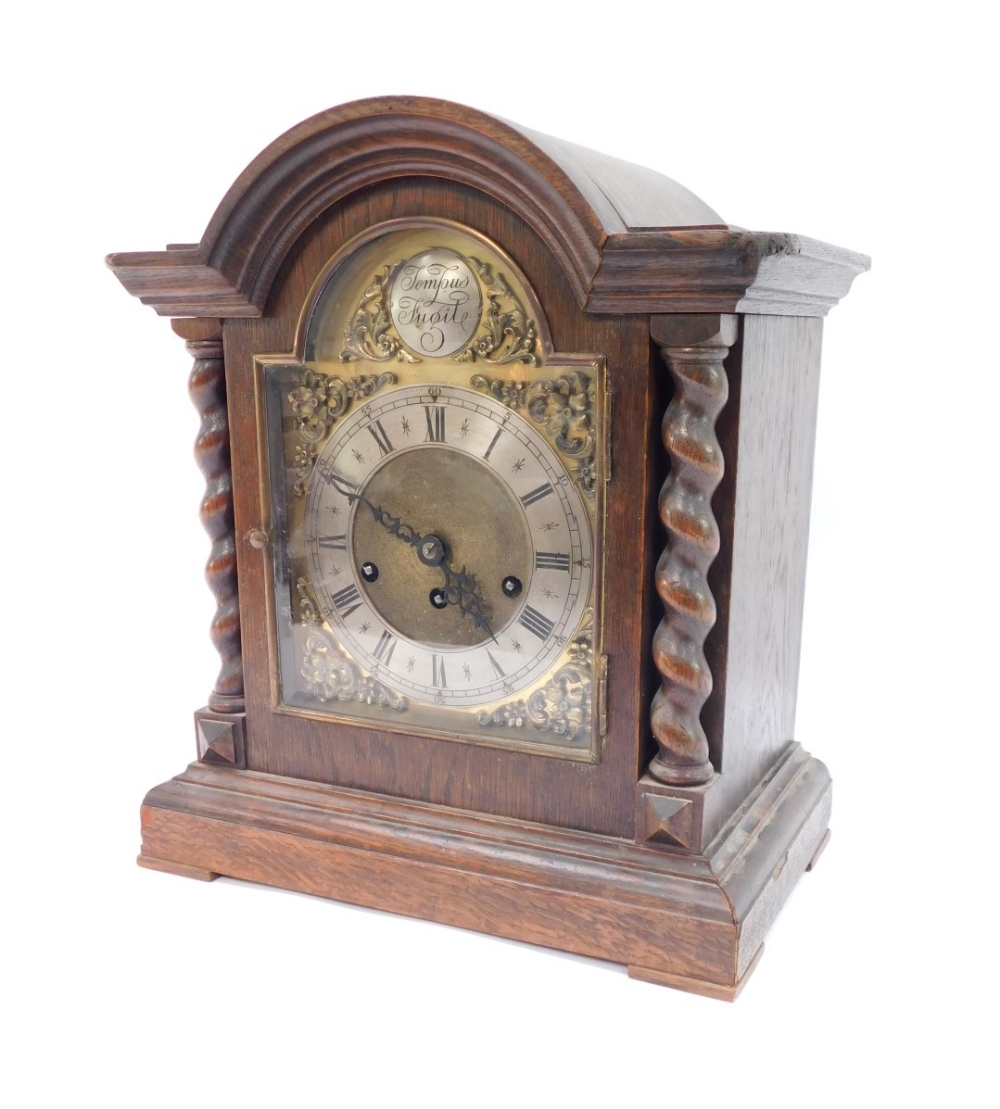 An early 20thC oak cased mantel clock, the arched top with barley twist column supports, on a steppe