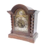 An early 20thC oak cased mantel clock, the arched top with barley twist column supports, on a steppe