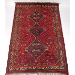 A Persian rug, with a central pole medallion in black on a red ground with multiple borders, 264cm x