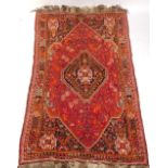 A Persian Shiraz type carpet, with a central medallion on a red ground decorated with flowers, leave