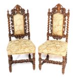 A pair of late 19thC carved oak side chairs, each with gold upholstered back and seat, with barley t