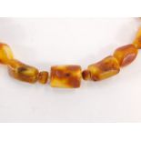 An amber necklace, with various sized and coloured amber stones, some oblong some oval, with clear p