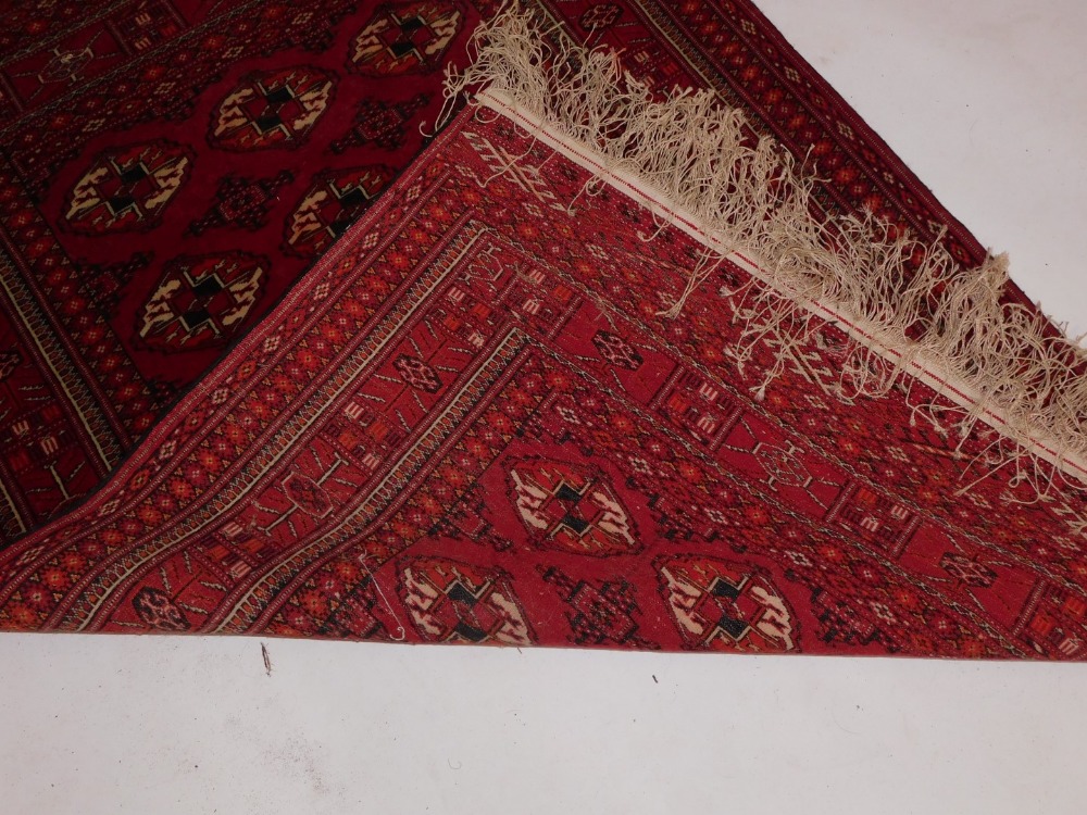 An Afghan Belouch rug, with three rows of medallions on a red ground, within multiple borders, 106cm - Image 3 of 3