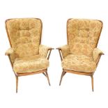 A pair of Ercol style upholstered wingback armchairs, each with a light elm finish and applied and b